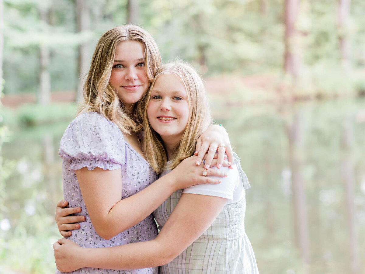 Two sisters hugging closely and looking at the camera for a portrait.