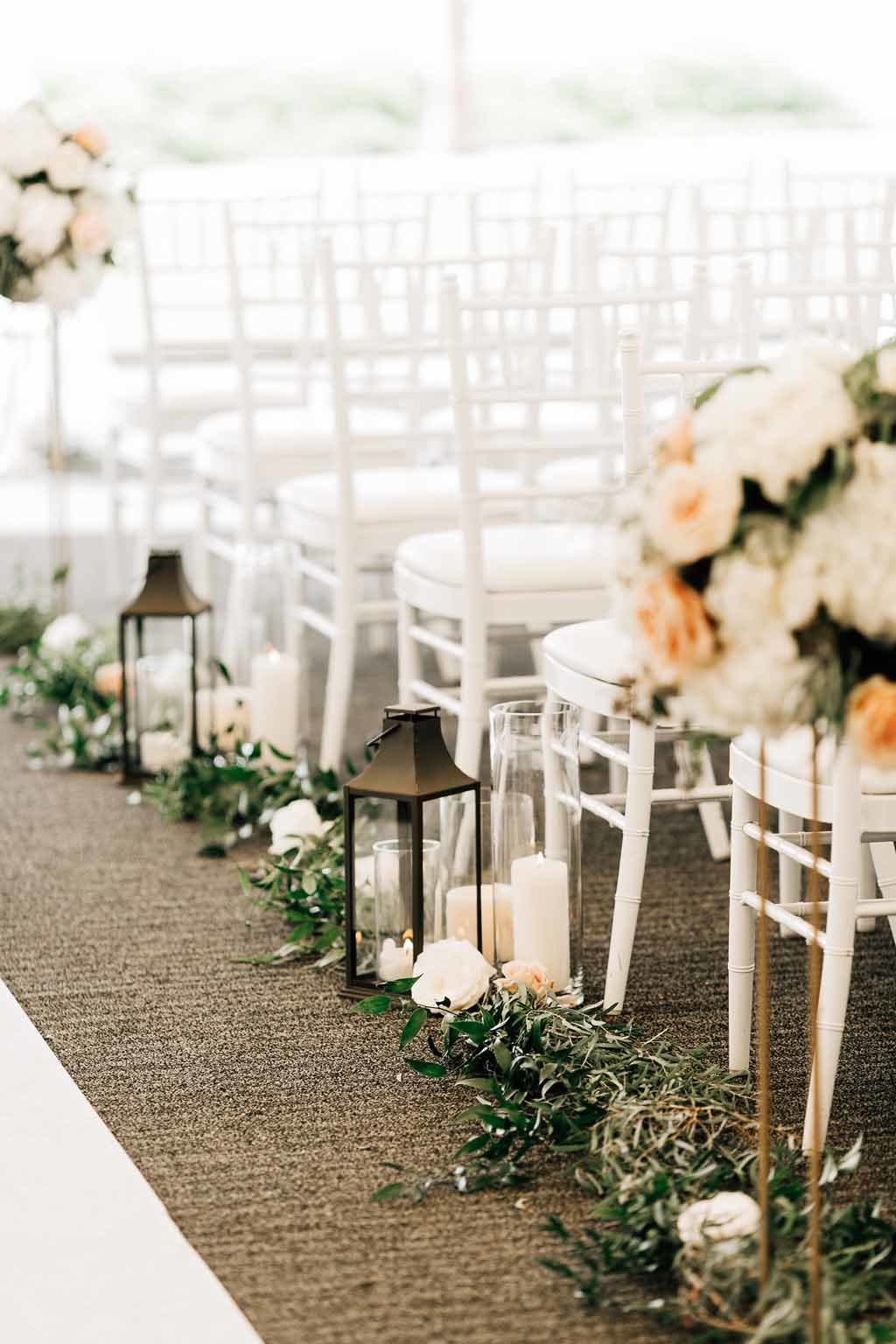Lanterns,  pillar candles  and greenery garlands line the aisle of this tent wedding in Seattle.