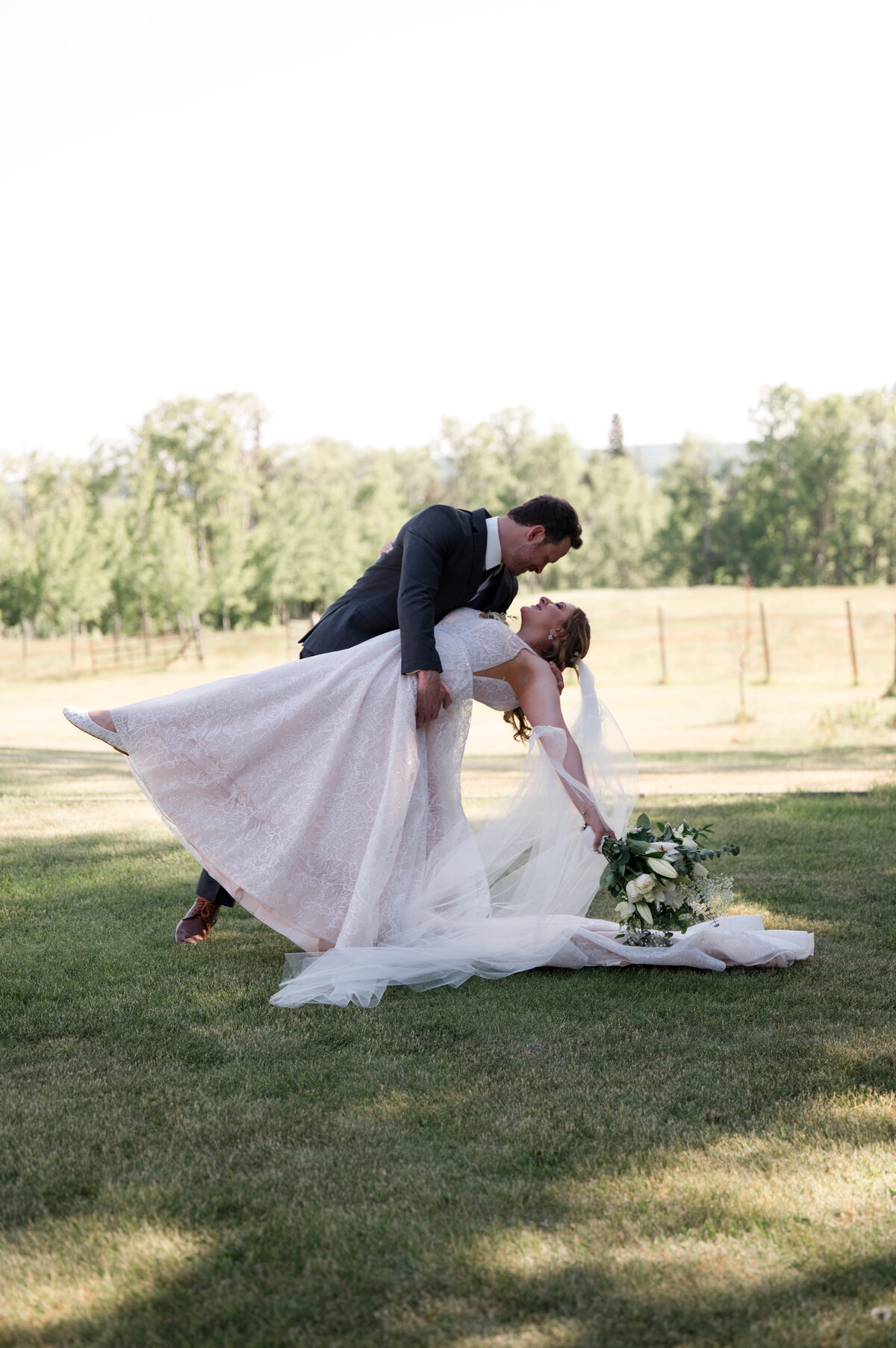 groom dipping his bride in a sunny field
