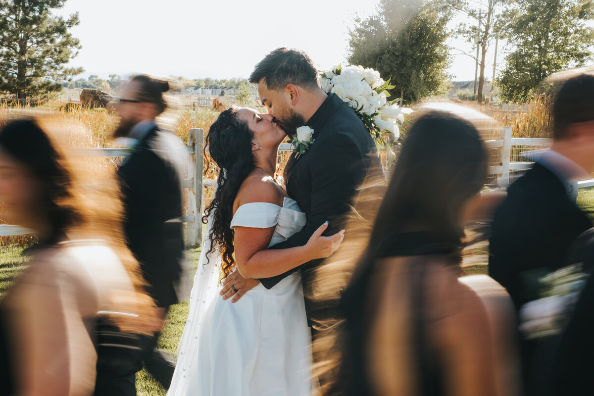 Couple kissing among their wedding party