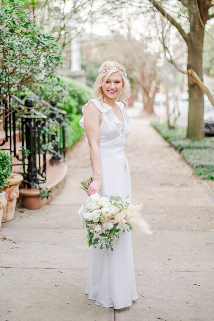 A Bride stands with her flowers on a sidewalk in downtown Savannah, GA.