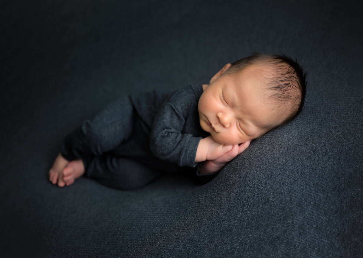 Bremerton newborn photo session with newborn sleeping on his side with hands under his cheek.