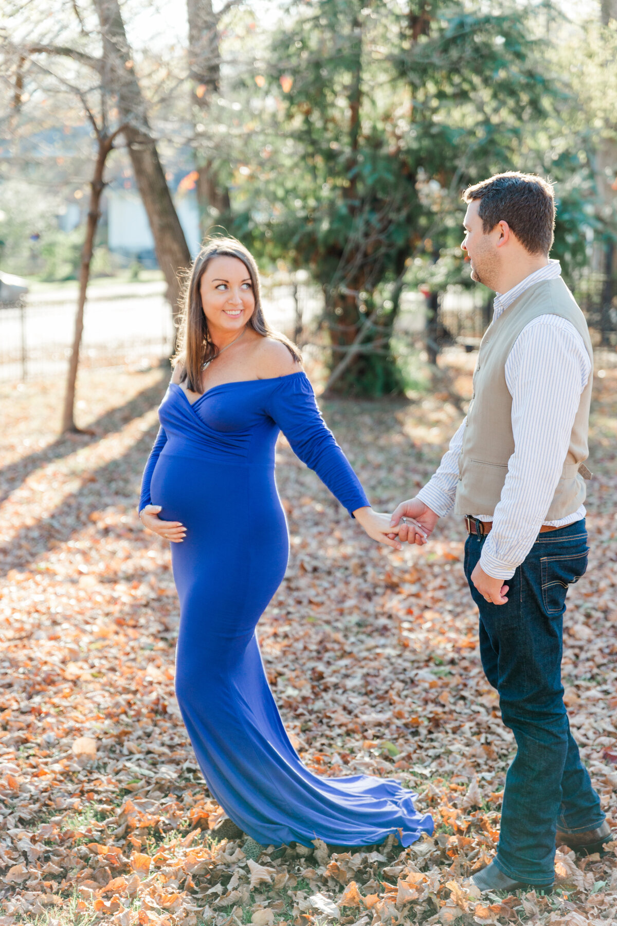 a pregnant woman in blue gown walks with husband