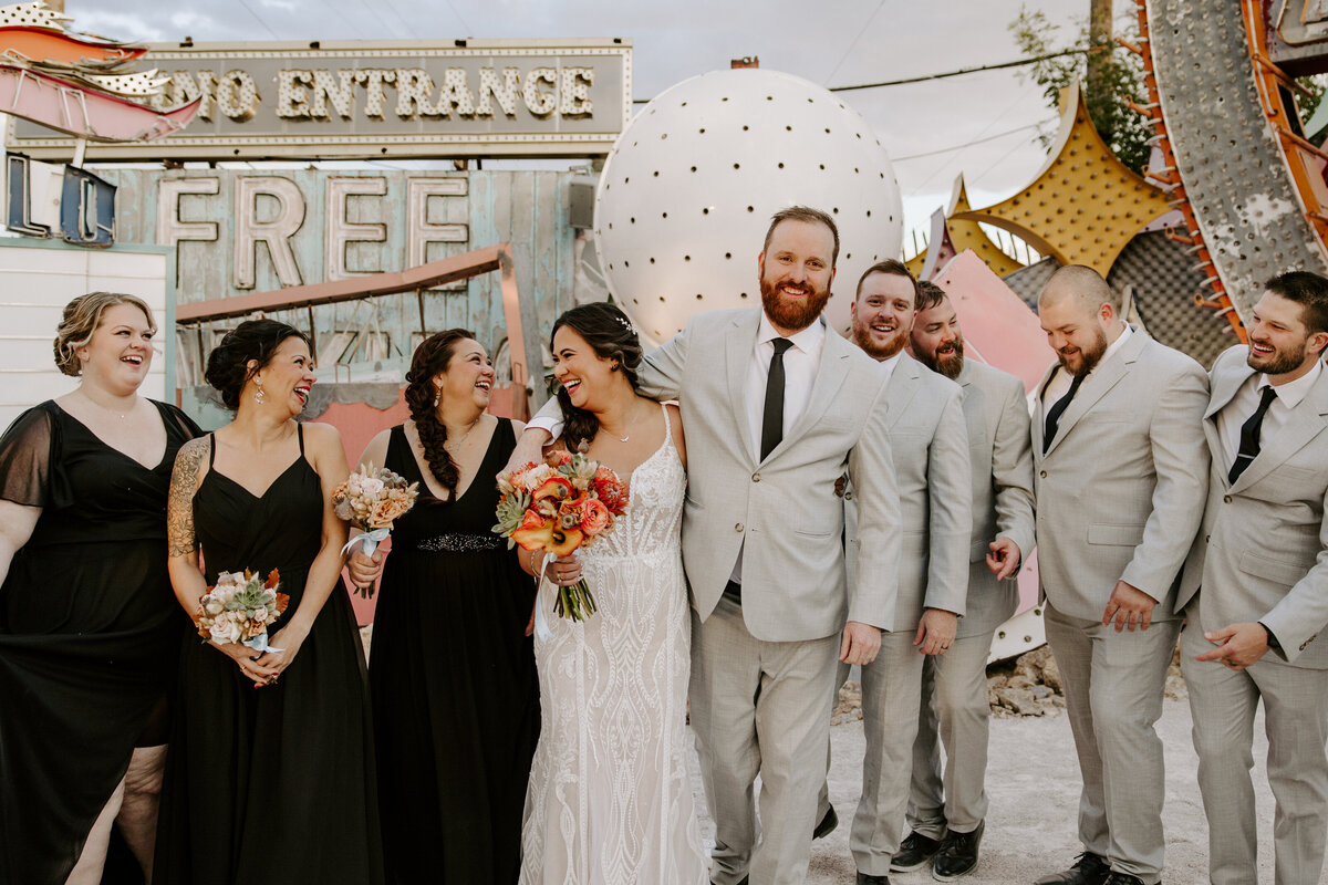 A couple poses with their wedding party at The Neon Musuem.