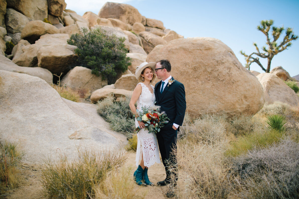 A bride and groom stand together in Joshua Tree national park