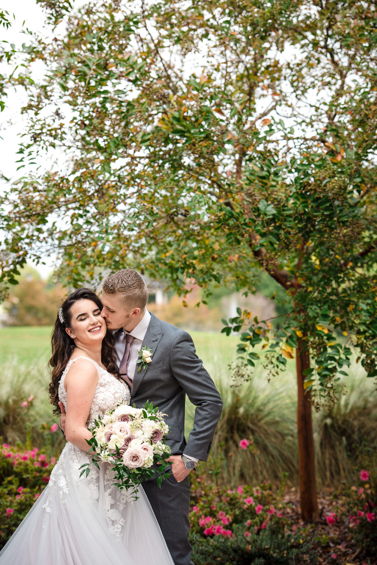 Russian groom kissing bride's cheek outside in the garden of at the Ballantyne Hotel by Charlotte wedding photographer DeLong Photography