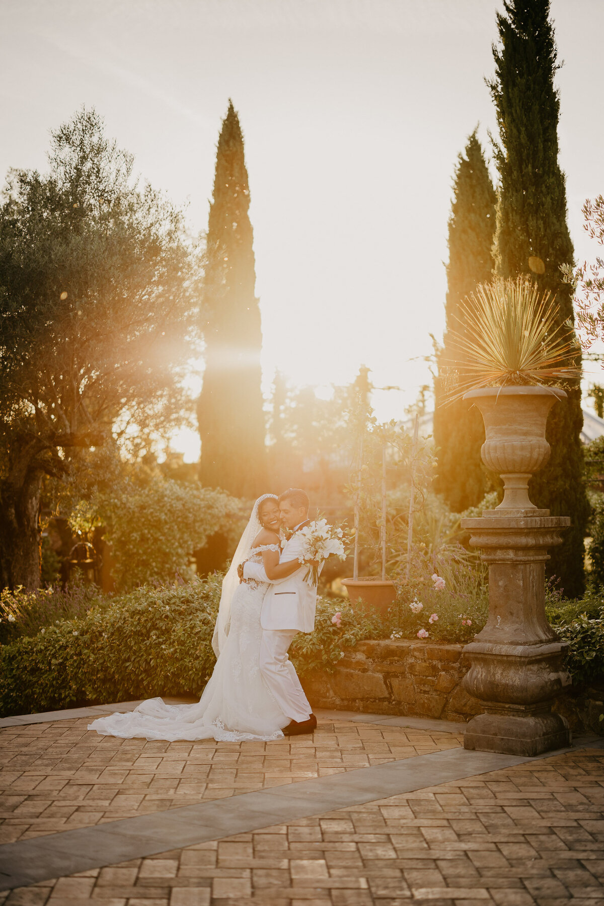 Bride and groom kissing at sunset in the gardens of Tenuta Corbinaia, elegant wedding in Tuscany.