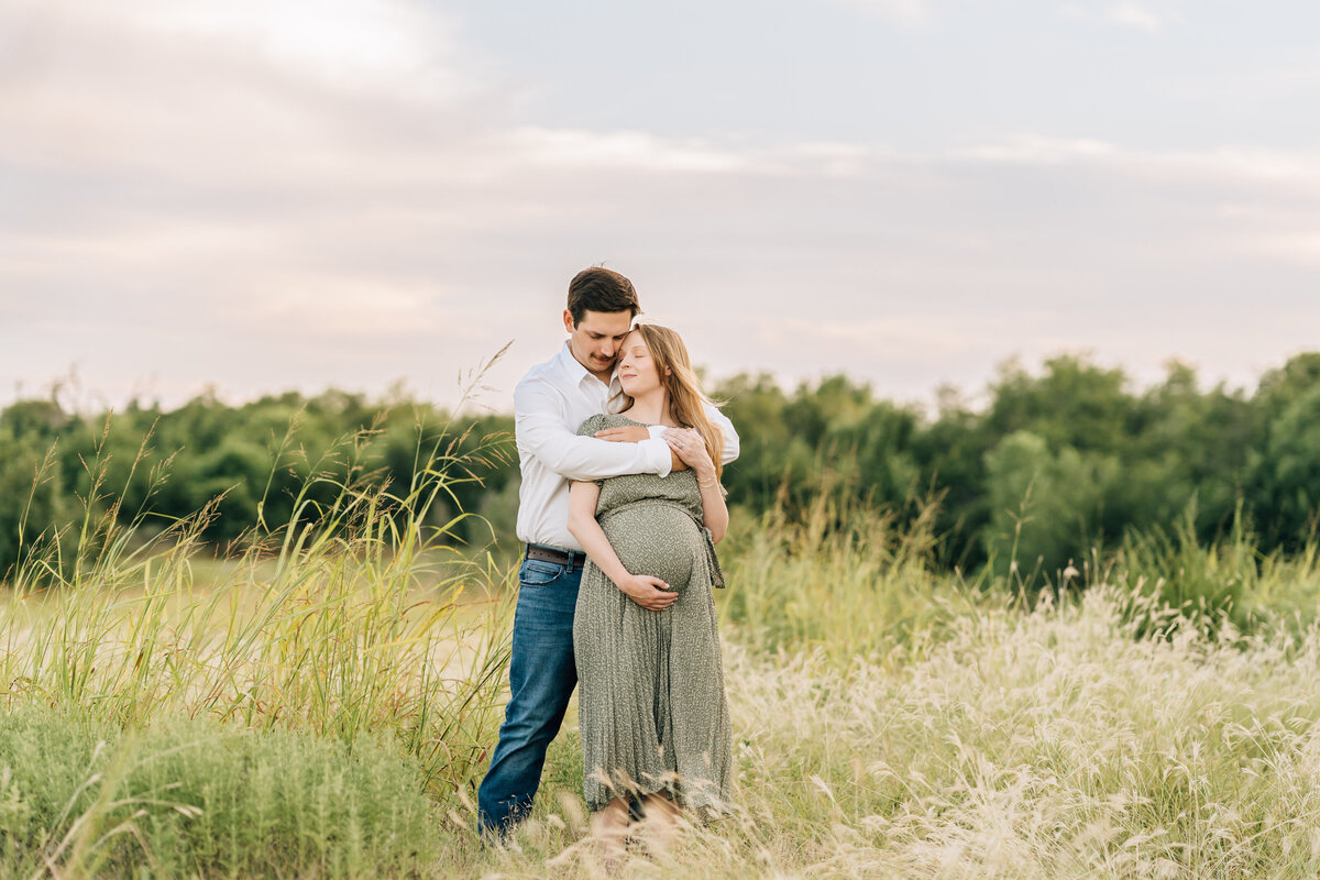 pregnant woman embracing husband in a field