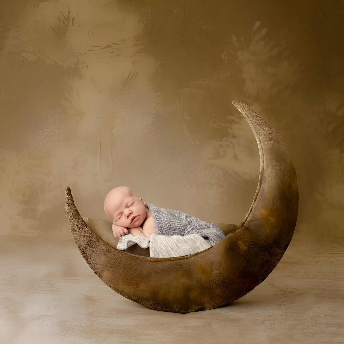Baby boy lays asleep in a wooden crescent shaped bed