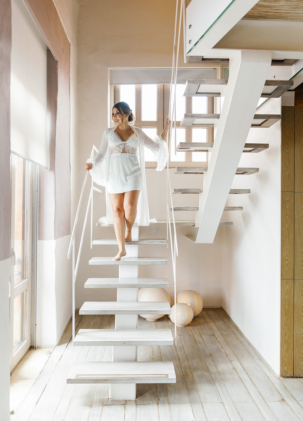 Victoria steps gracefully down a white staircase in her bridal robe, preparing for her Cartagena Colombia wedding.