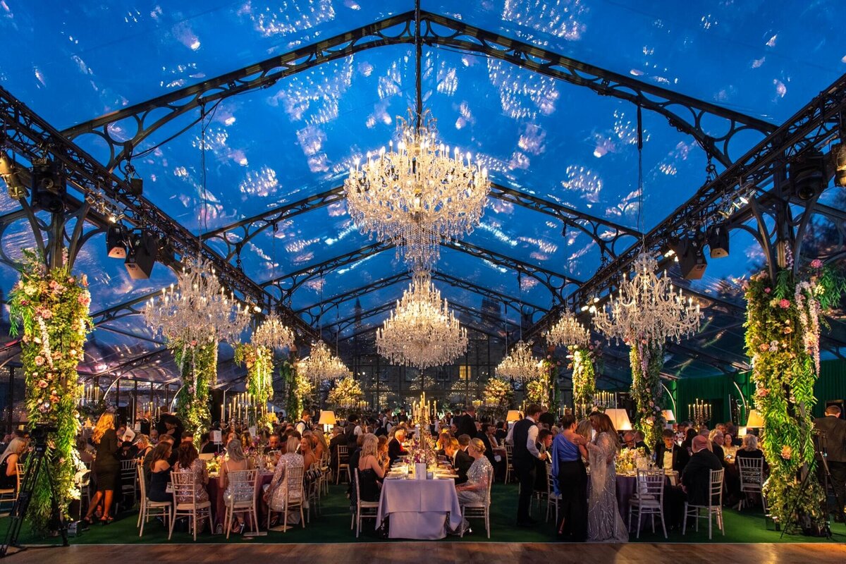 An aerial view of a glass marquee on a lawn with a long walkway and flowers at the entrance for Amelia and Olly Murs