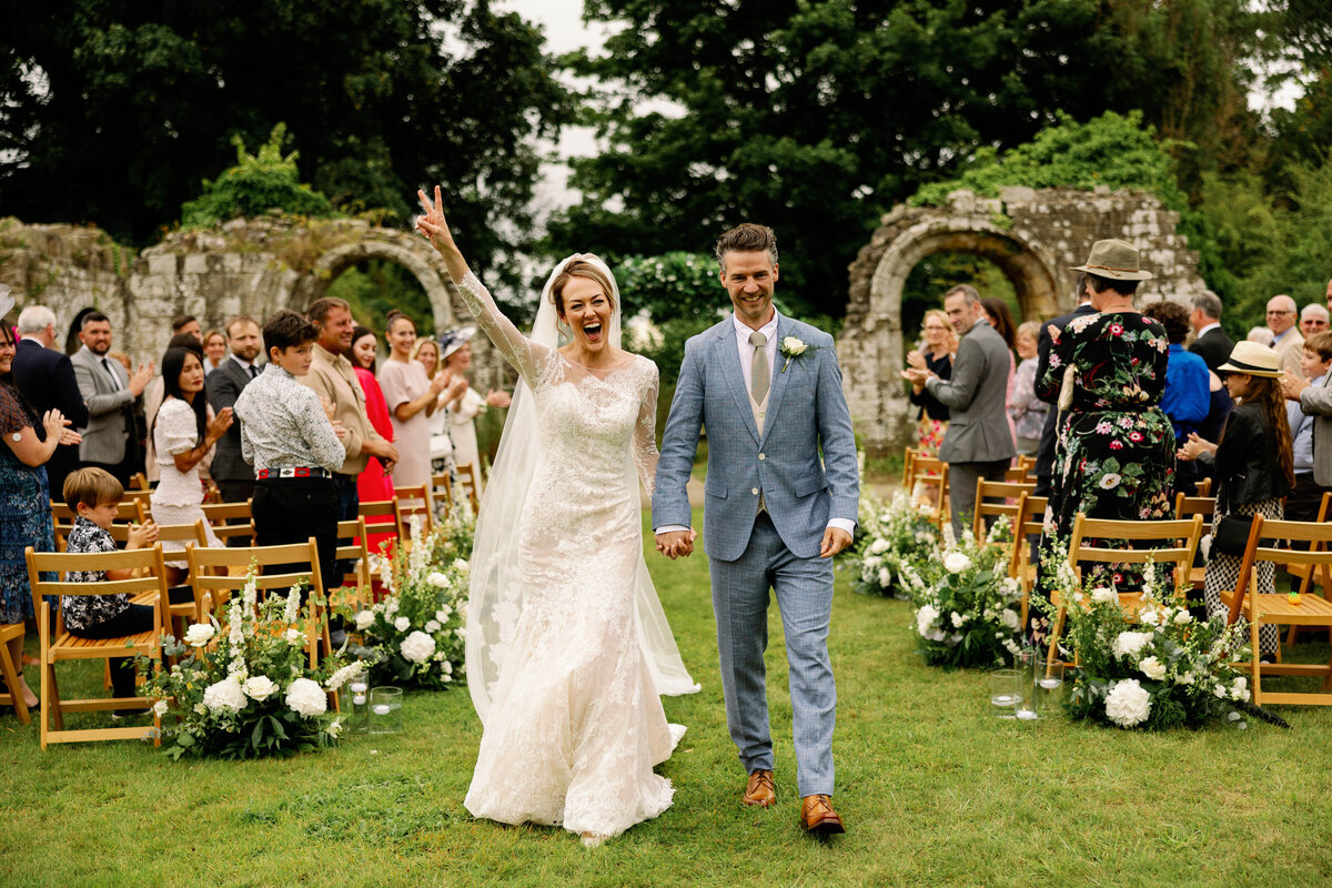 Fun photograph of a bride and groom as they exit the ceremony at Jervaulx Abbey