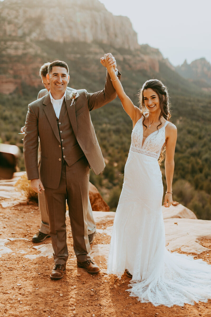 man and woman raise arms after getting married