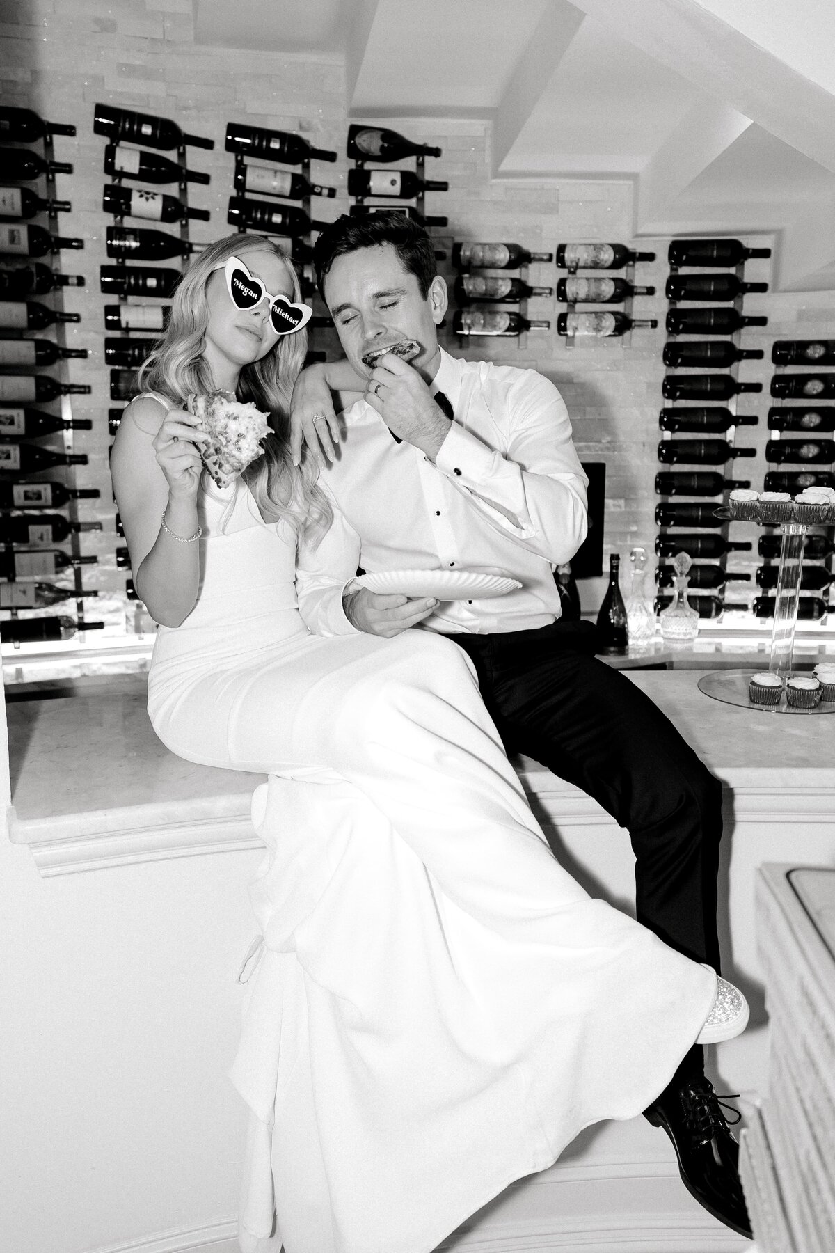 bride and groom eat pizza and pose in front of wine cellar