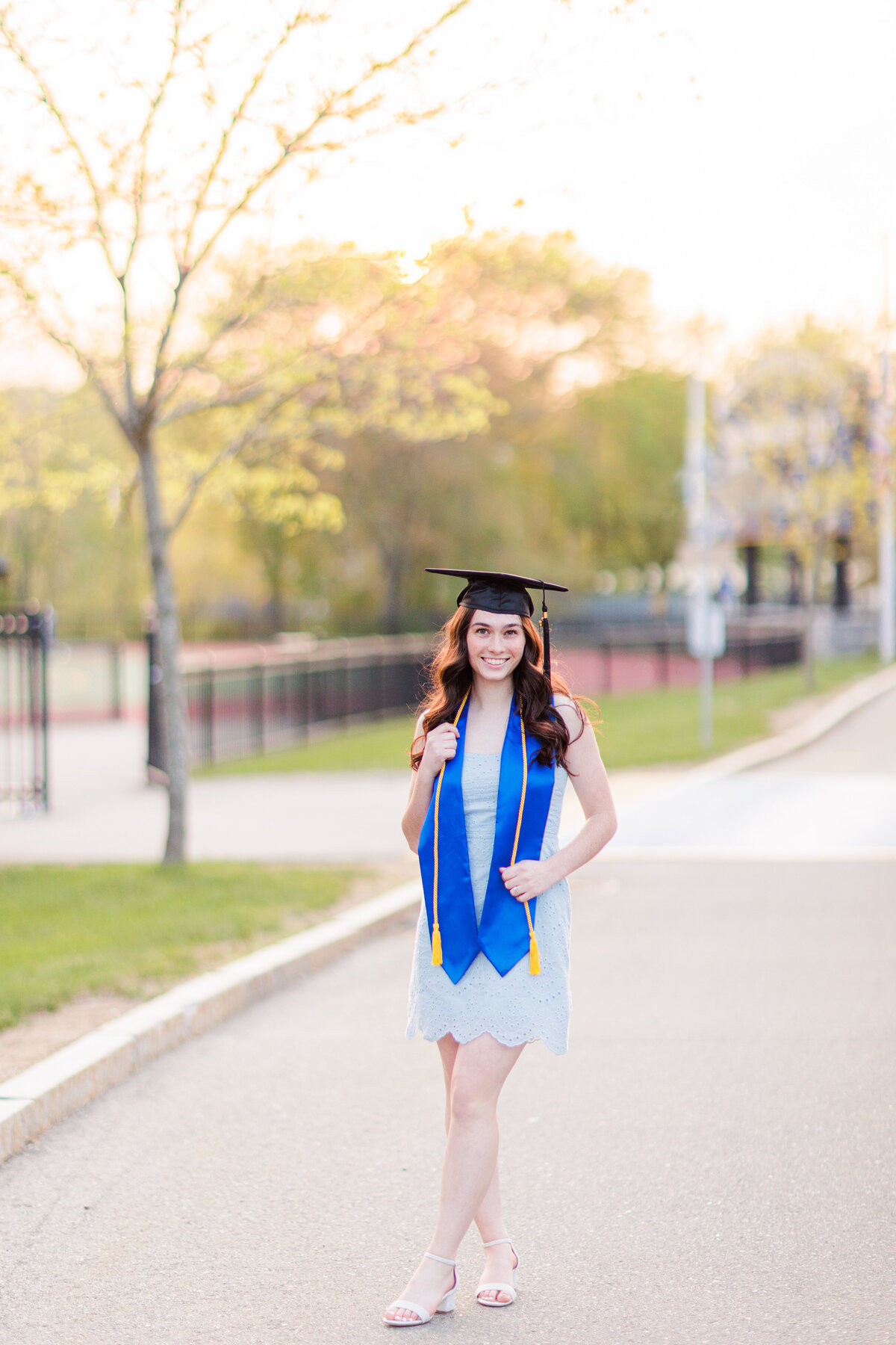 A girl holding her graduation cords representing a Boston cap and gown photographer