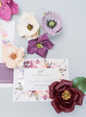 wedding stationery suite flat lay featuring jewel toned sugar flowers including roses tulips poppies hellebroes and ranunculus - luxury sugar flower wedding cake toppers by kelsie cakes