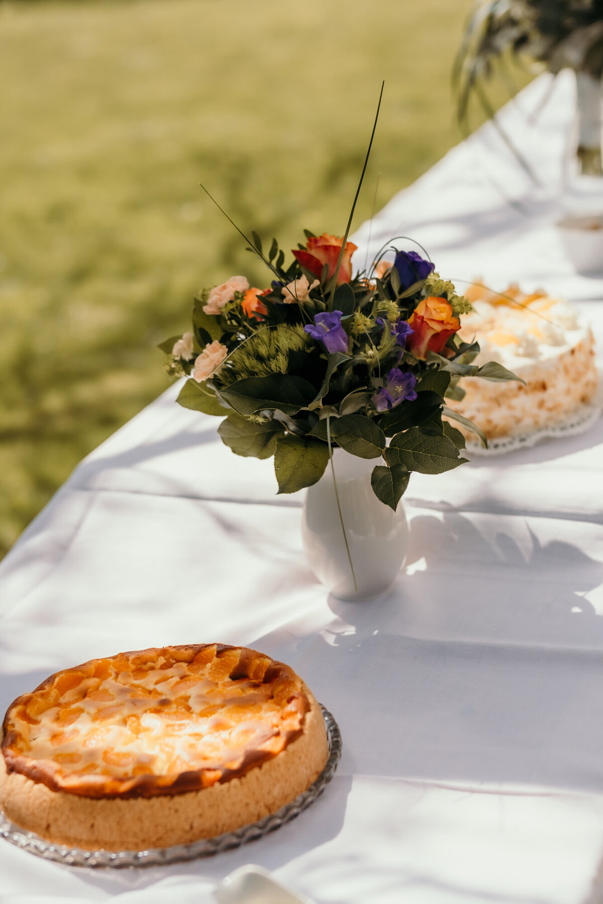 Die Kuchen stehen für die Gäste draußen bereit auf einem Tisch mit einer weißen Tischdecke.