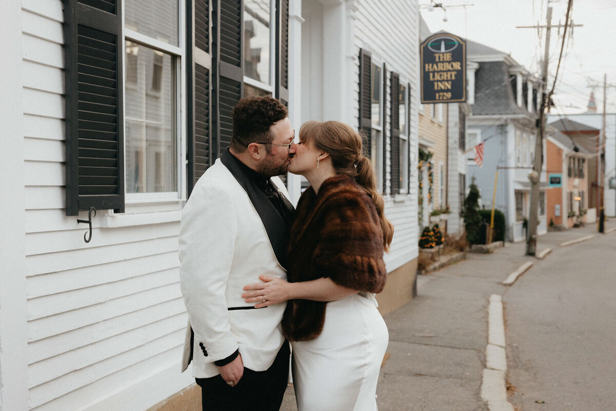 Bride and groom sharing a kiss in front of a black barn door