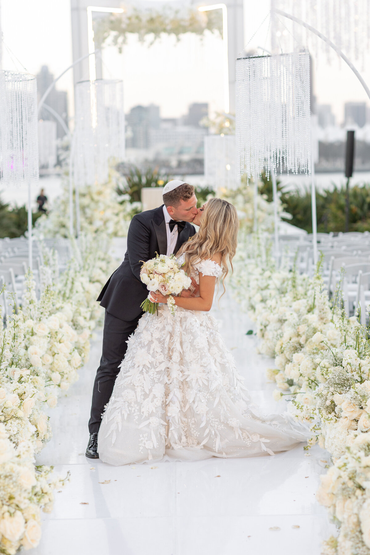 A bride and groom kissing in the middle of an aisle