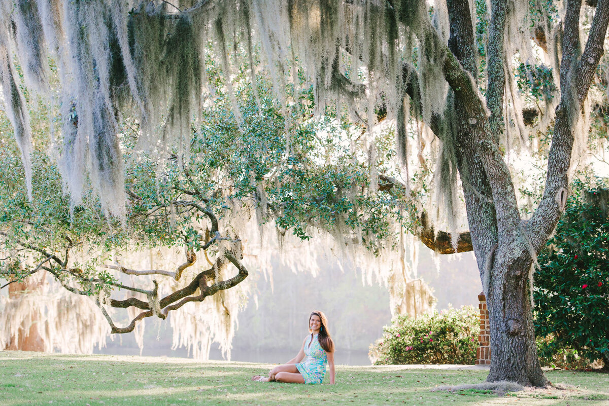 High school senior walking beneath moss-draped oaks in a dreamy Lowcountry landscape at Kiawah Island