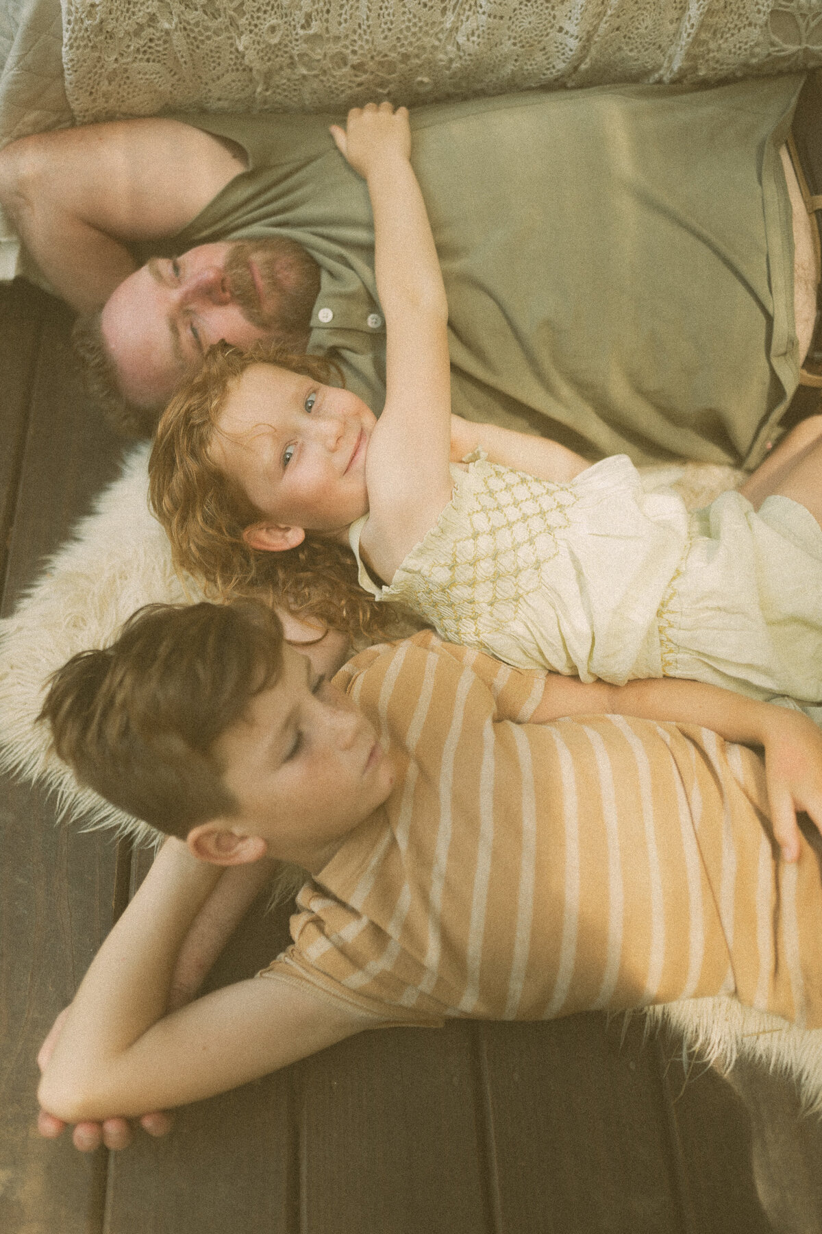 A dad lays with his two young kids in Das Hinterhaus. 