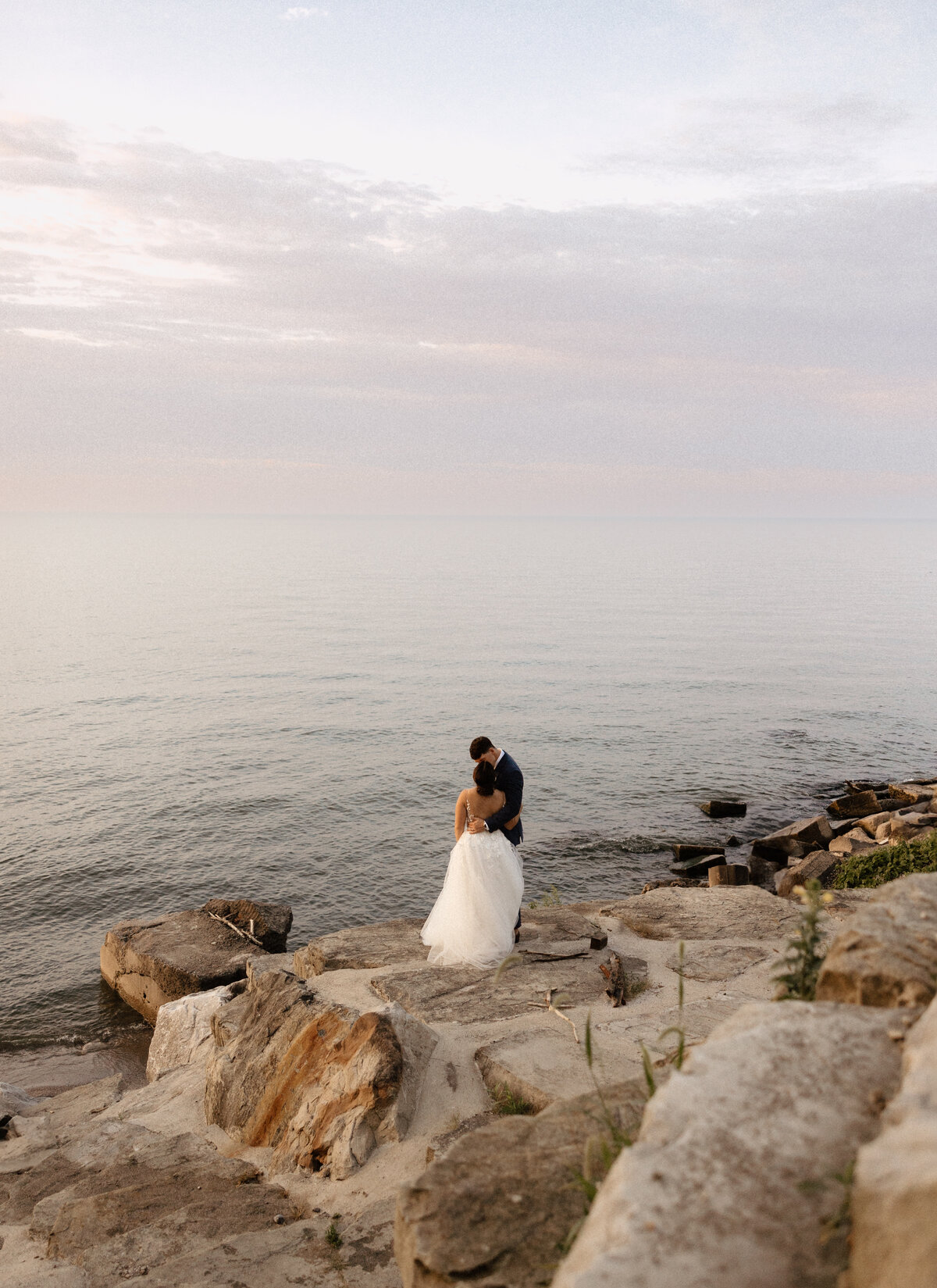 A couple embraces on the shore of Lake Erie for their wedding photos