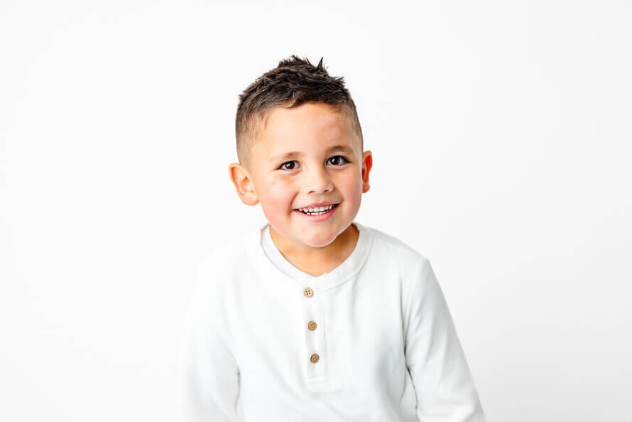Boy in a white studio smiles for his photos.