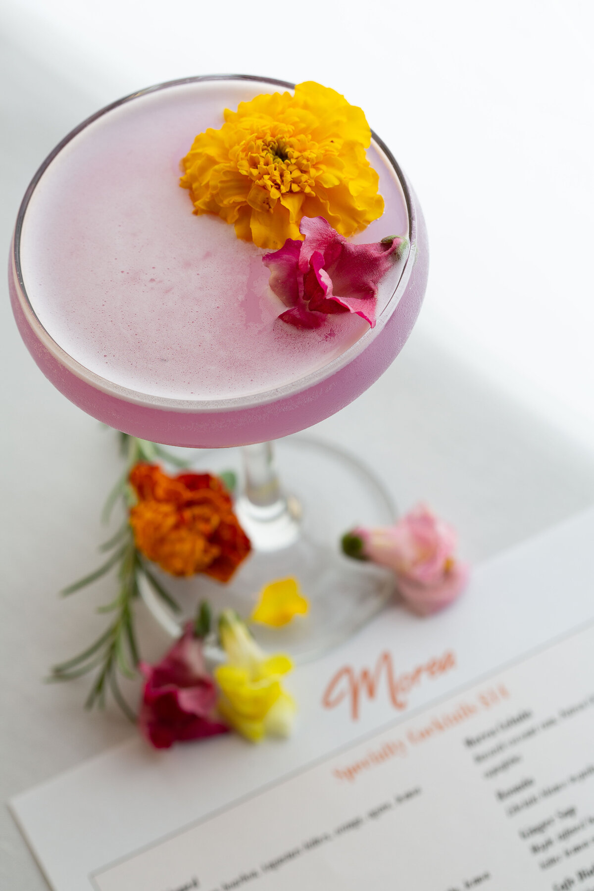 Pink cocktail topped with fresh flowers