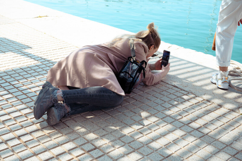A female is laying on the ground to capture the perfect shot