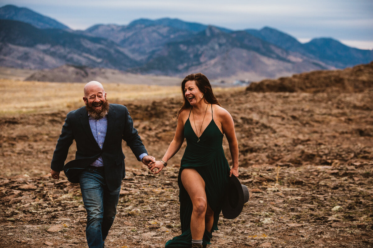 man and woman laugh and run through north table mountain colorado