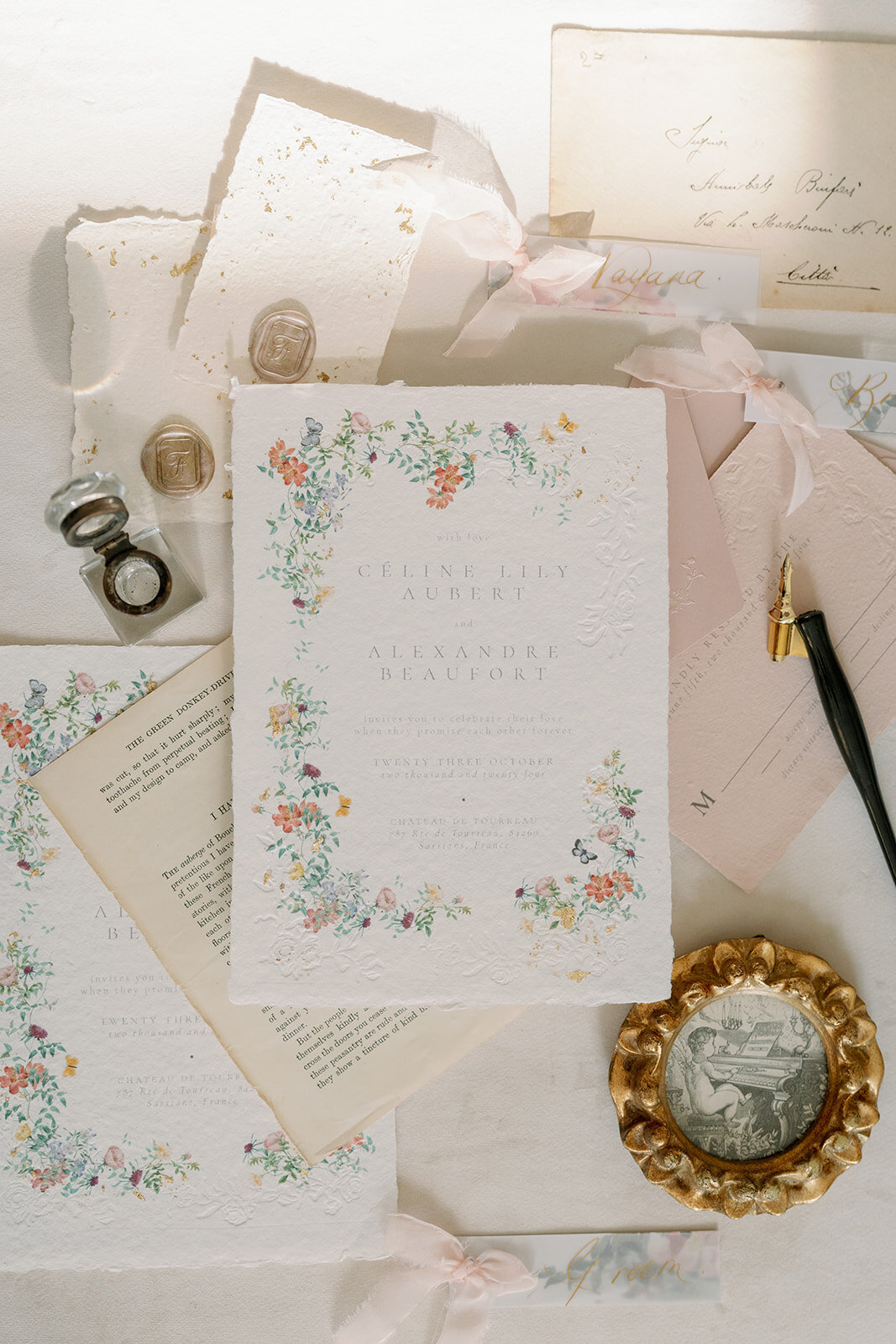 Hand-painted floral wedding stationery styled with vintage accents, ribbon, and rings at Château de Tourreau.