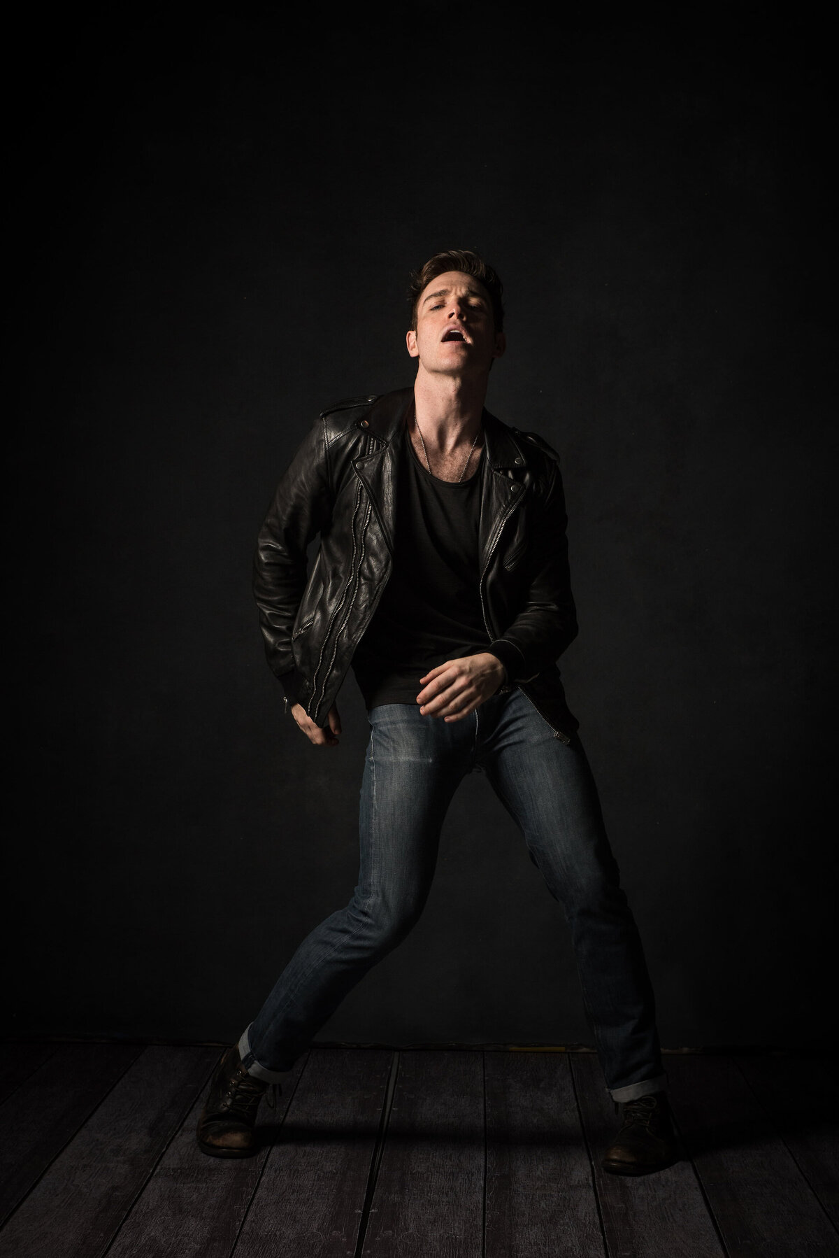 A man dancing in a leather jacket.