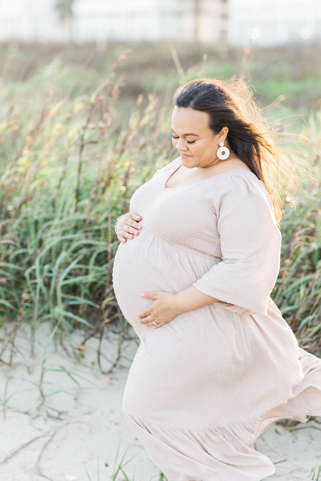 pregnant mama glances at belly on galveston beach