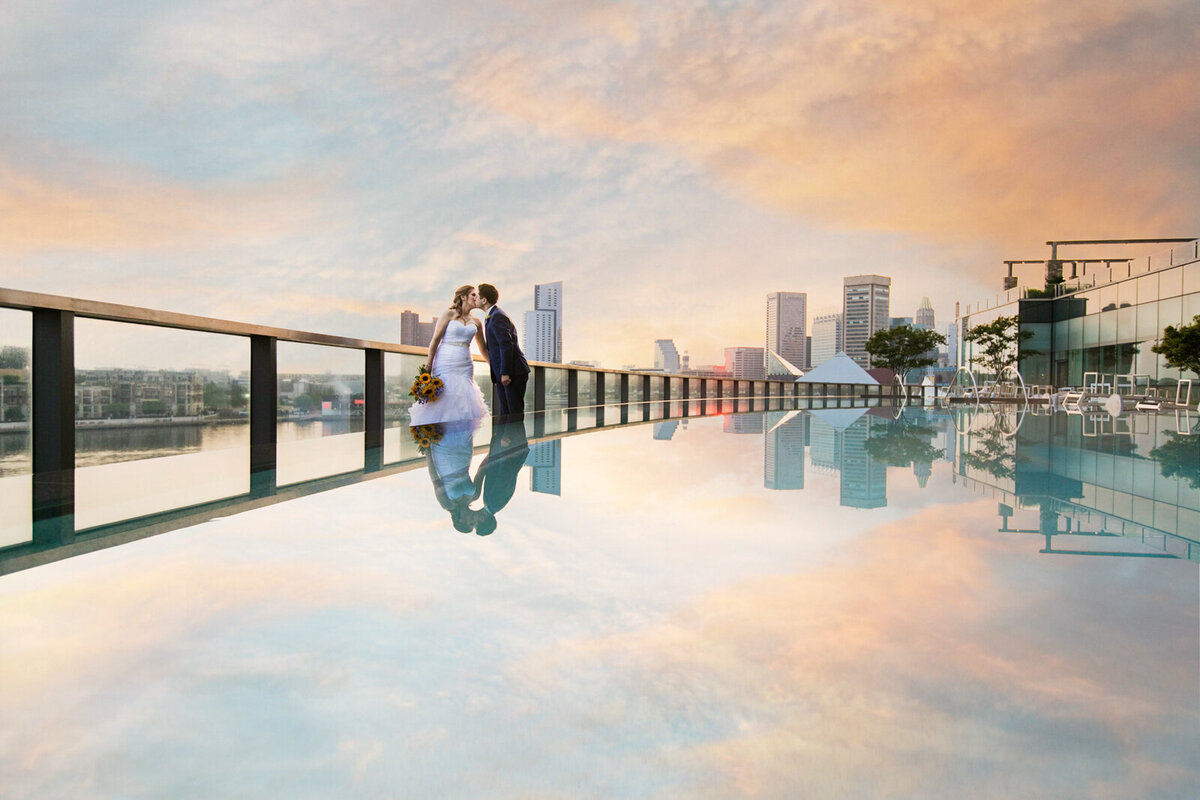 sunset reflecting in the Four Seasons Baltimore pool with a bride and groom kissing