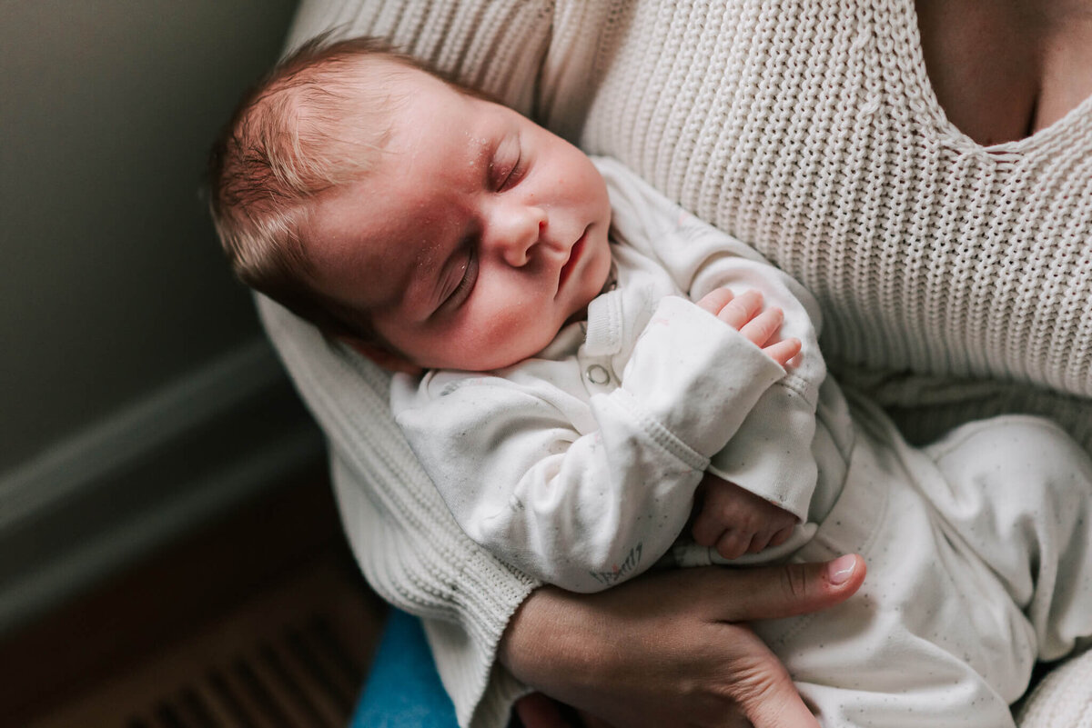sweetly sleeping newborn boy with his arms cuddled close together
