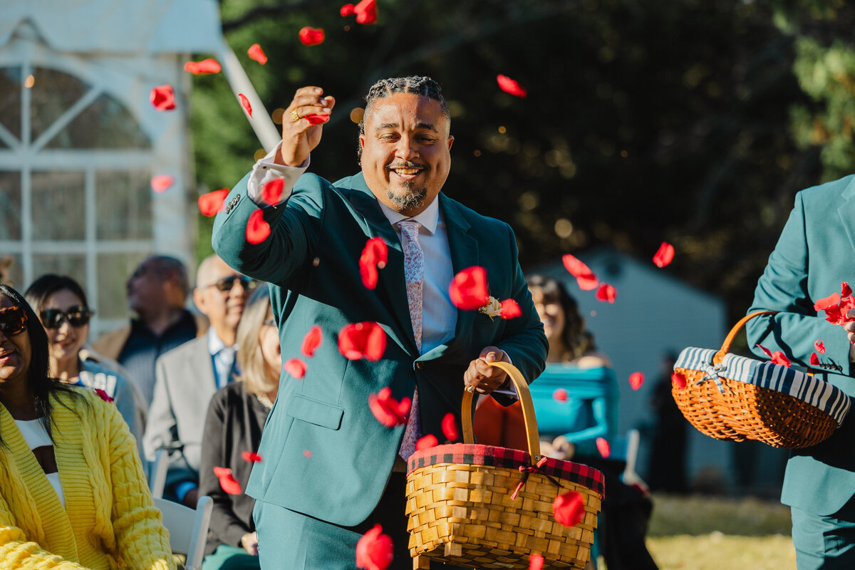 A person walking and throwing red rose petals from a basket 