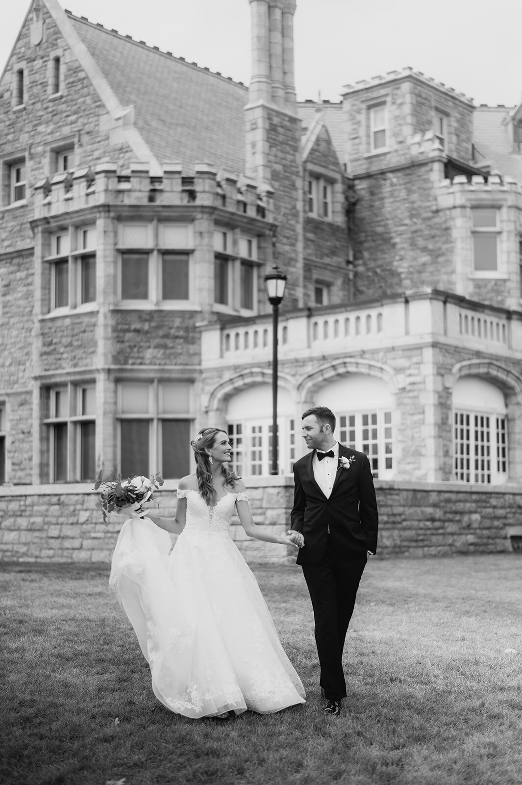 bride and groom walk hand in hand in front of their branford house wedding photo by cait fletcher photography