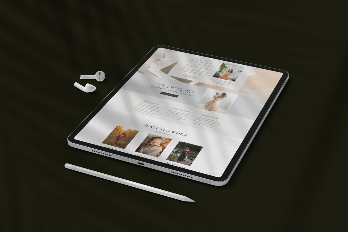 A tablet displaying a photography portfolio website, crafted by a web designer for small business, rests on a dark surface, accompanied by a stylus and wireless earbuds.