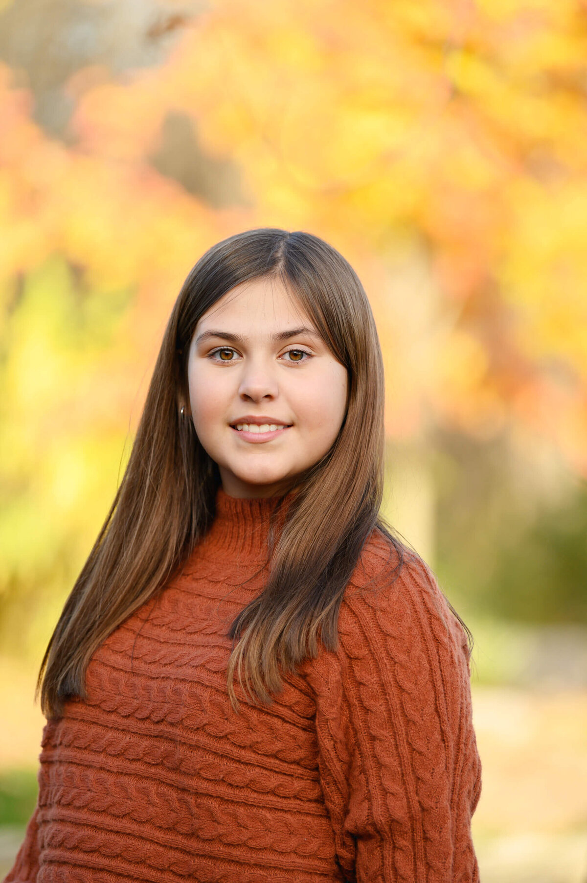 up close photo of a pre-teen wearing an orange sweater for her fall family photos