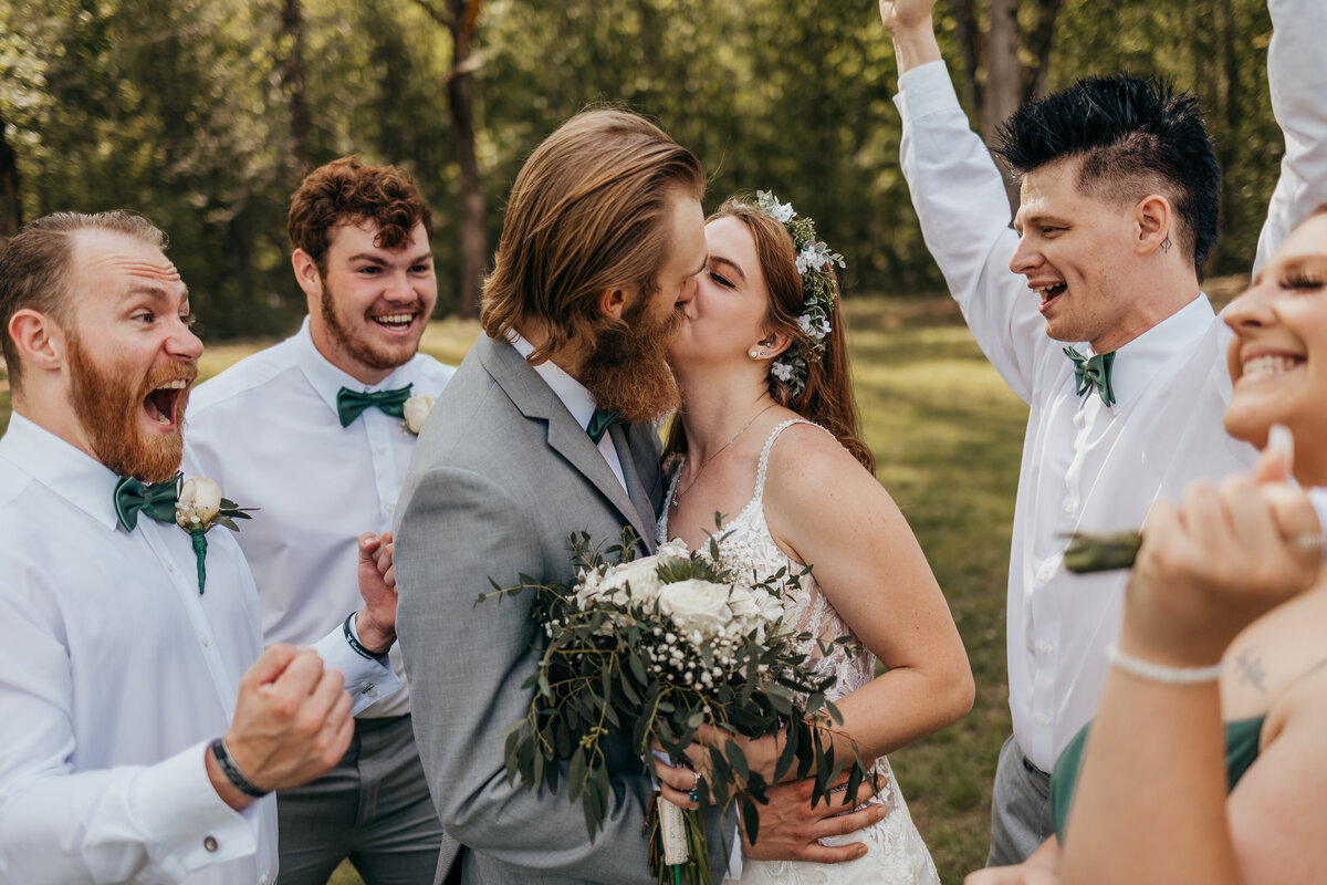 bride and groom kissing with people cheering