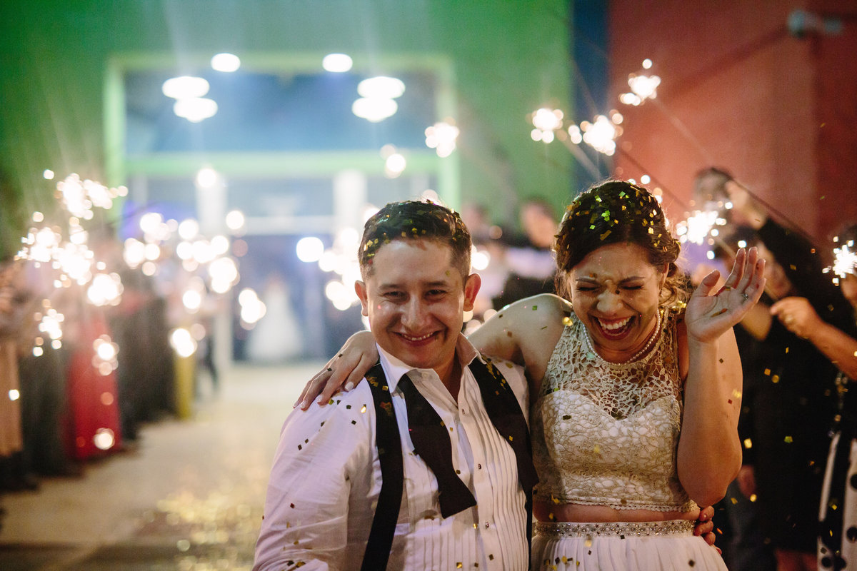 bride and groom leaving their wedding as guest shower them with golden confetti