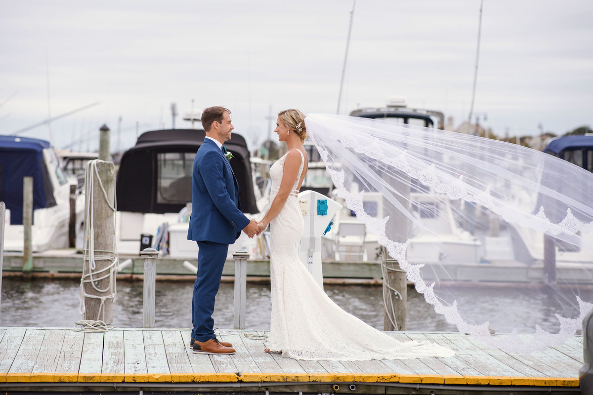 Bride and groom on dock with boats at Captain Bills