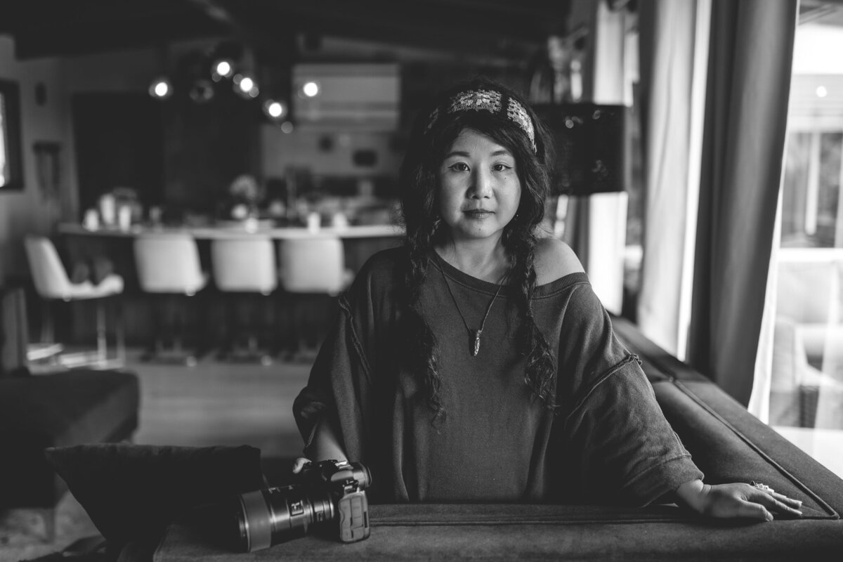 Lifestyle headshot of boho photographer with camera in black and white