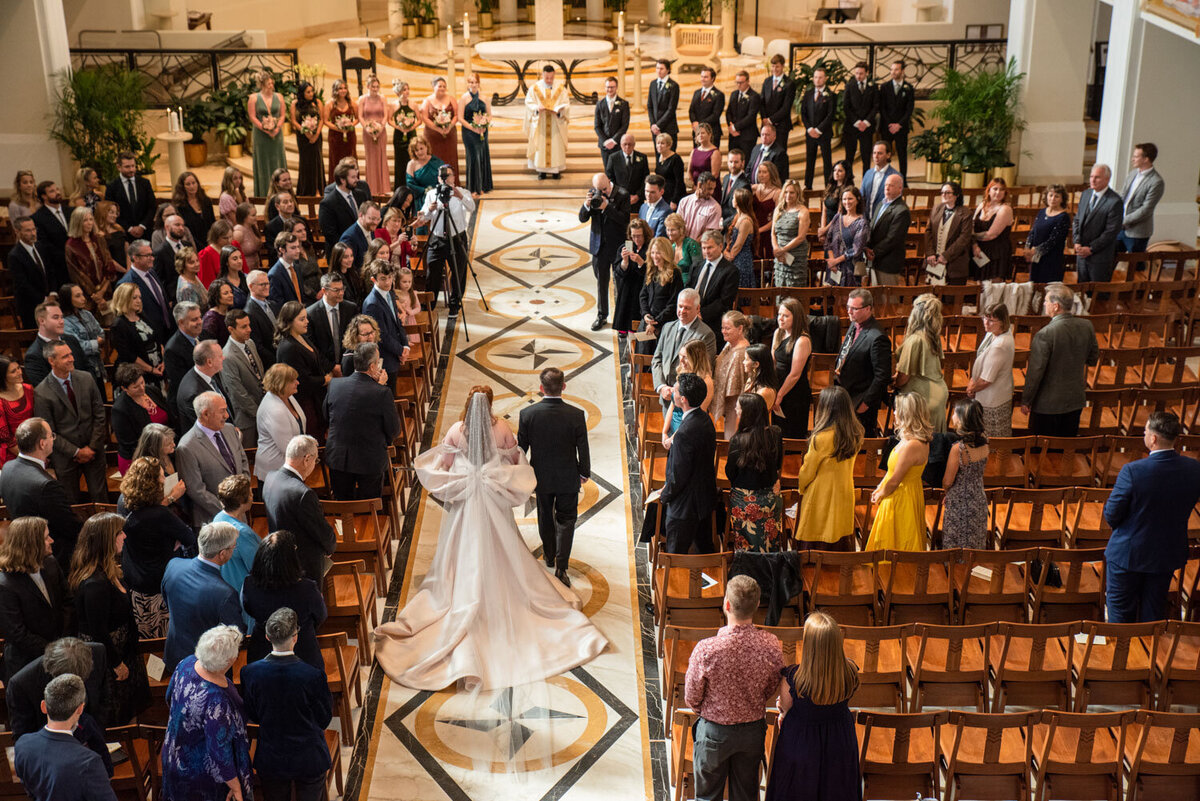 A bride and groom are walking down the aisle of a church