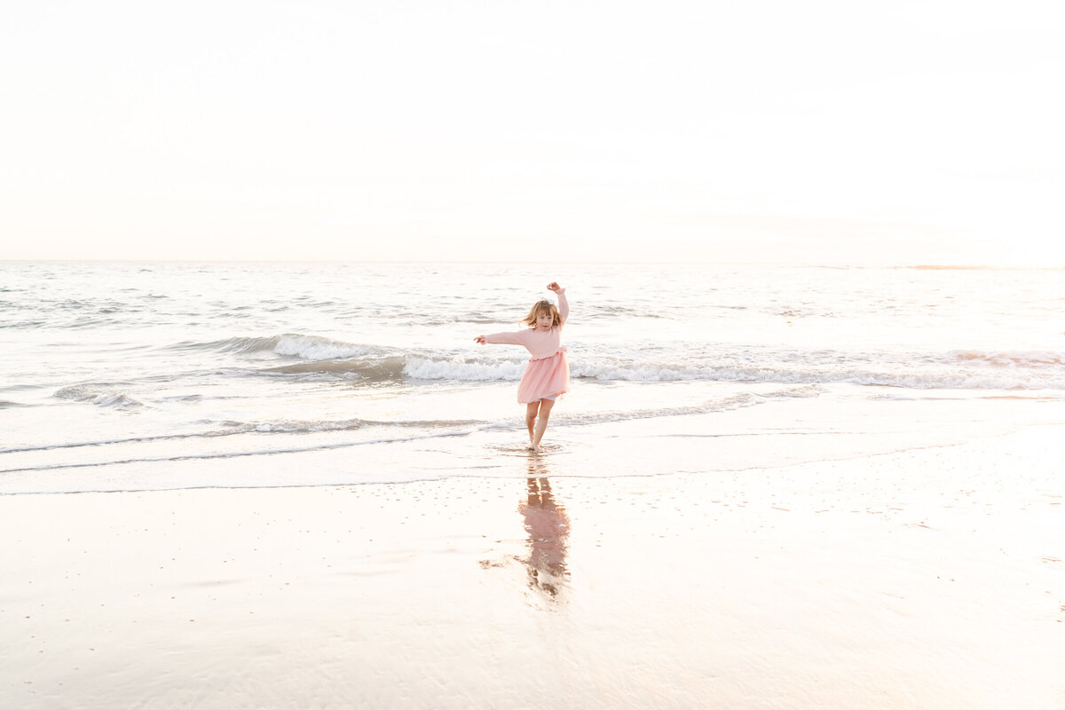 little girl running through the water at the beach during a photo session