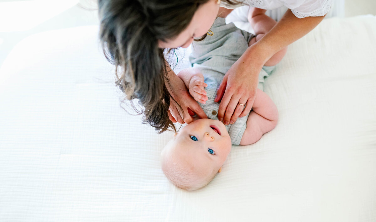 Mom is tickling the baby's chin while the baby is looking up. 