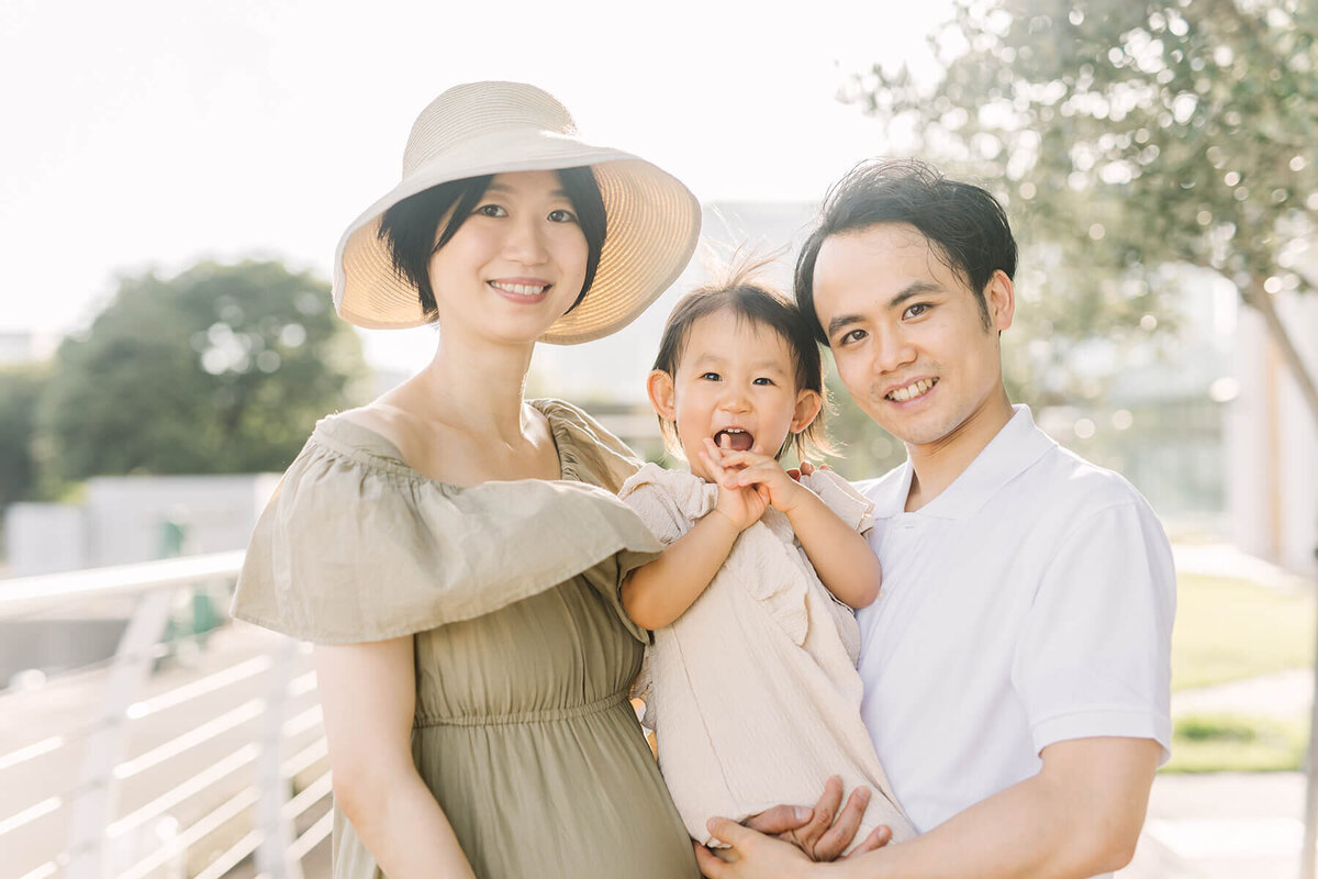 Tokyo maternity session by Yukika Ishikawa Photography. A pregnant mother and her husband and daughter all smiling and looiking in the camera with their heads close.
