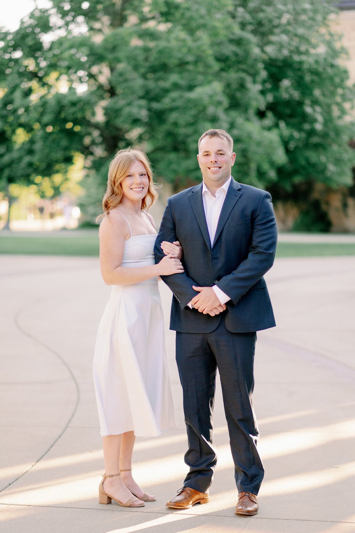 engaged couple standing with their arms linked