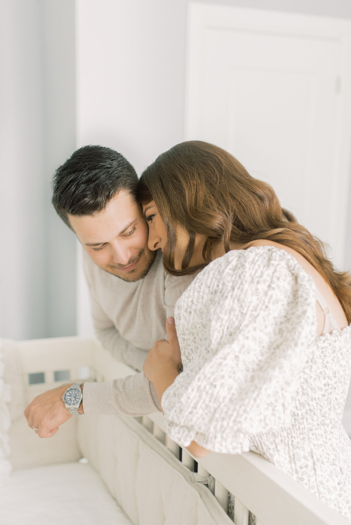New parents smiling over crib, sharing a tender moment with their baby girl – soft and emotional storytelling by Christine Grace