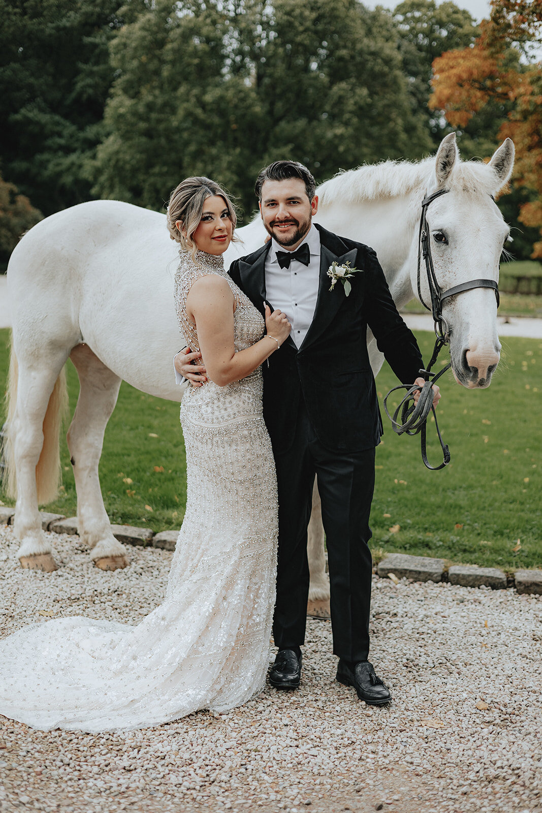 Bride and groom posing in front of white horse
